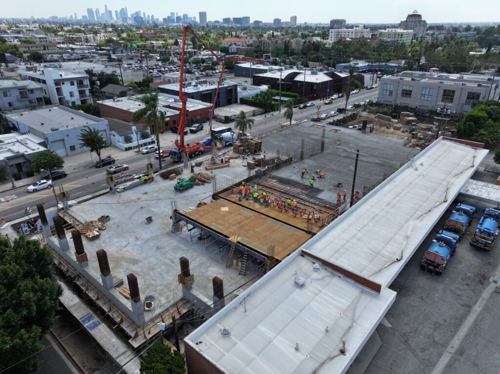Urban concrete slab pour with crews, pump truck, and surrounding buildings