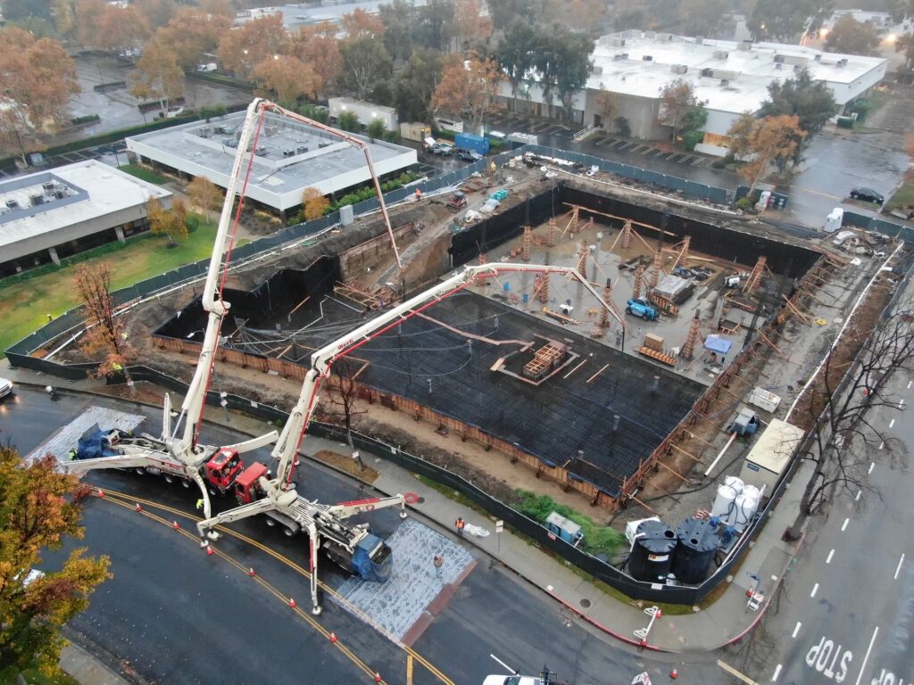 Concrete pump trucks operating inside deep excavation on urban construction site