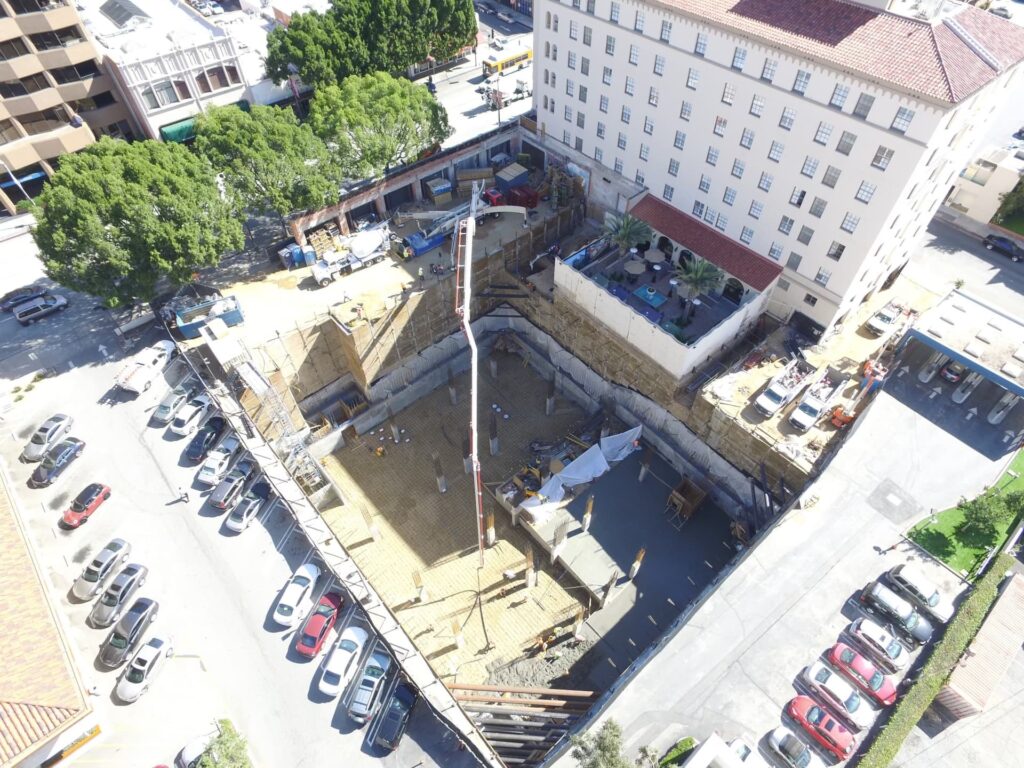 Construction crew working inside deep excavation with shoring and heavy equipment