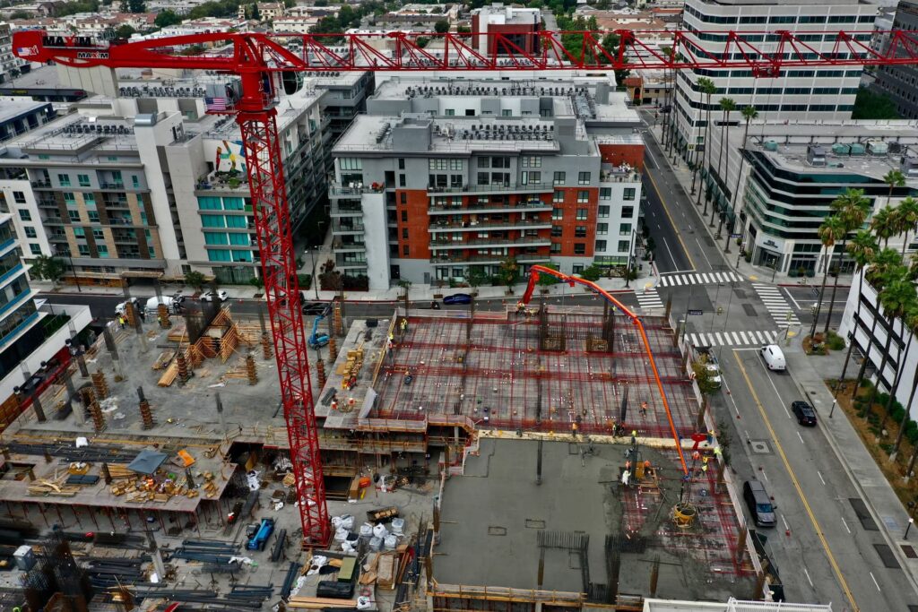 Tower crane overlooking concrete podium slab construction in urban setting