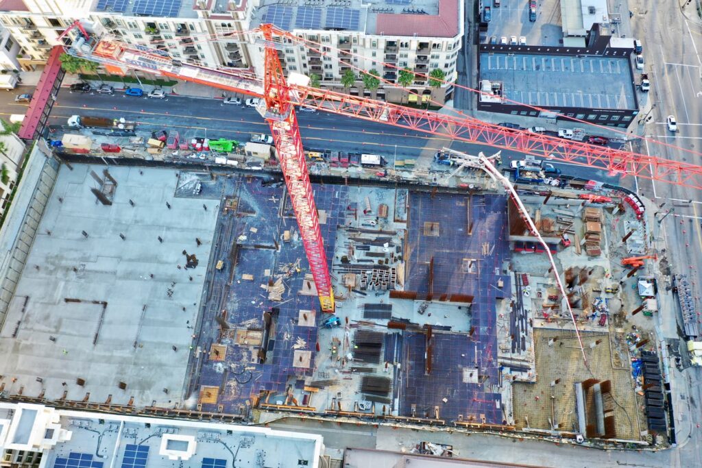 Aerial view of concrete podium construction with tower crane and pump truck